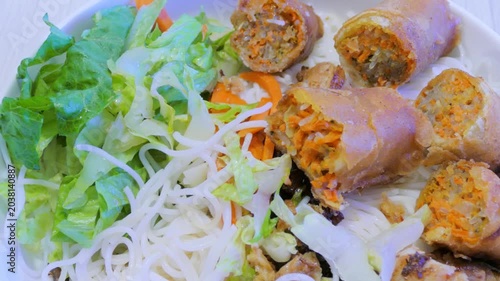 Close up view of golden brown fried spring rolls cut in half, revealing a savory pork and shredded carrot filling
