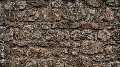 Rustic Weathered Ancient Stone Wall Texture Detail. Close up of a rugged old stone wall with grey and brown rock textures