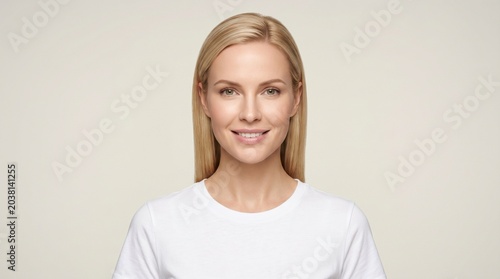Radiant blonde woman smiling in a white cotton tee. Portrait of a happy young woman with clear skin and natural makeup