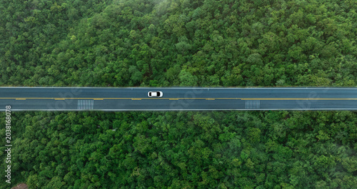 Konstfotografi Aerial view of dark green forest road and white electric car Natural landscape a