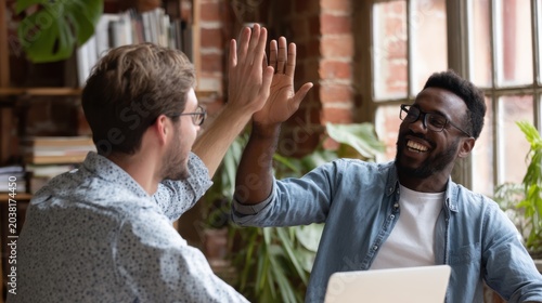 Colleagues Celebrating High-Five in Modern Office with Brick Wall Background