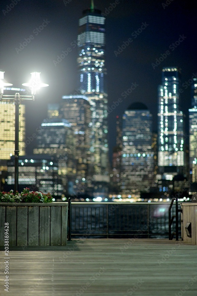 Obraz premium Calm Seaside Walkway With Soft City Lights And Distant Skyscraper Illumination new york