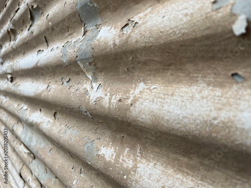 Angled old beige metal wall with peeling paint background. Vintage Industrial Texture of Flaking Paint on Ribbed Iron Panel. Galvanized Steel Sheet with Rusty Paint.