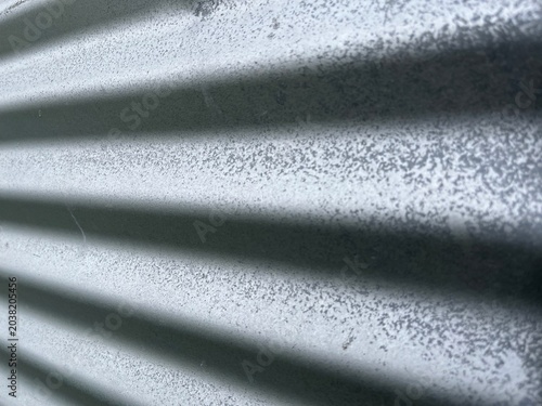 Angled silver corrugated metal wall with sharp front and blurry back. Industrial Galvanized Steel Sheet Close Up with Diagonal Wave Pattern. Grey Galvanized Metal Sheet.