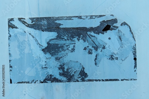 Bilde på lerret Abstract background of a torn and weathered blue sticker residue on a metallic s