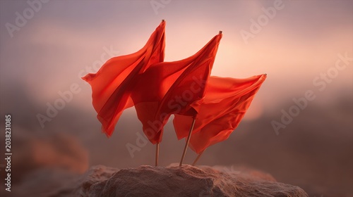 Three red flags waving dramatically on a rocky outcrop at sunset.