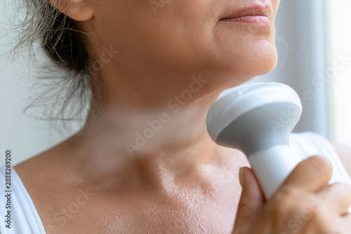 Neck jawline skin sweat fan cooling relief menopause hot flush mature woman hand closeup light daylight window pores sheen air comfort wellness health selfcare heat temperature care skincare