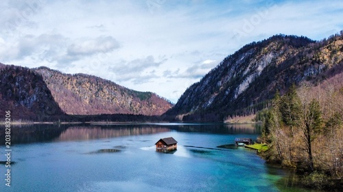 Foto Idyllischer Blick auf ein einsames Holzbootshaus in einem türkisfarbenen Bergsee