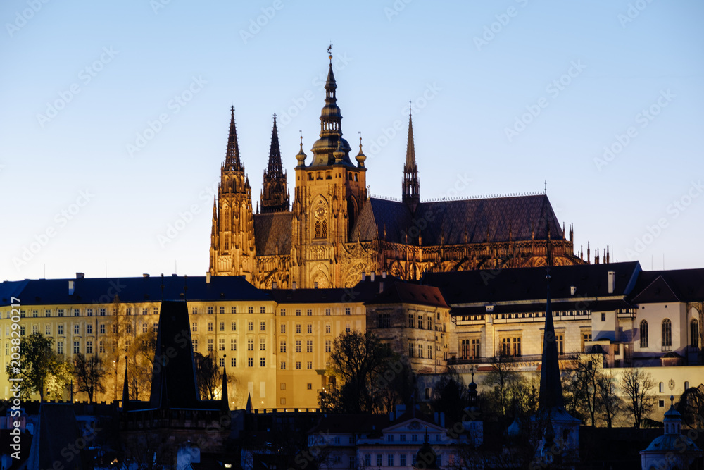 Naklejka premium As the sun sets over Prague, the majestic Prague Castle stands illuminated against the twilight sky.
