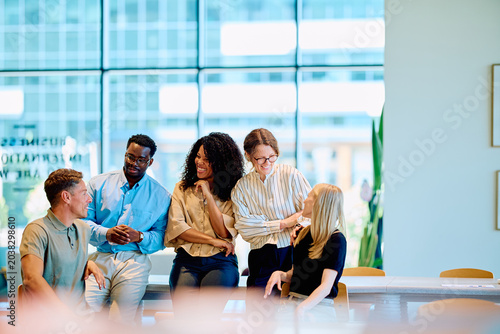Foto Diverse business professionals smiling and talking during an informal meeting, r