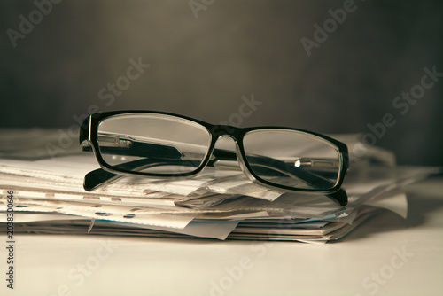 Stack of newspapers and eyeglasses