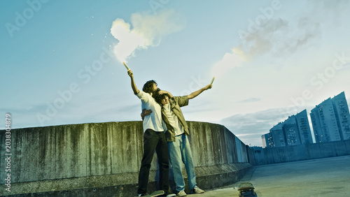Foto A skateboarder in an urban setting holds a flare and torch aloft, embodying a carefree lifestyle against modern apartment buildings