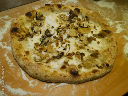 Pizza gourmet bianca con funghi, noci e formaggio su pala di legno infarinata 3014