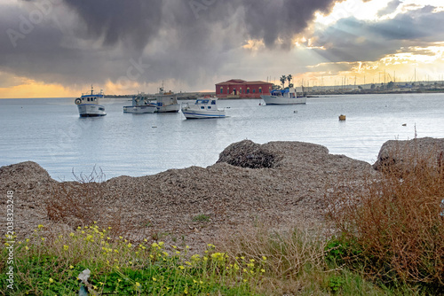 Marzamemi, Piccolo porto di pescatori con barche ancorate sotto un cielo drammatico al tramonto 4884