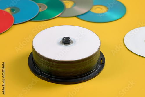 Tableau sur toile Many compact discs for laser player or computer  in plastic holder on yellow background