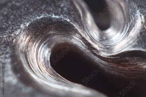 Close-up macro shot of metal texture, showing intricate layers and a wave-like pattern created by machinery