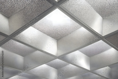 A modern suspended ceiling with recessed lighting creates a bright and airy atmosphere in the room. The grid pattern of the ceiling tiles, combined with the illuminated panels.