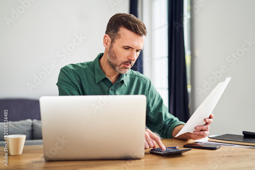 Worried man doing paperwork calculating finaces
