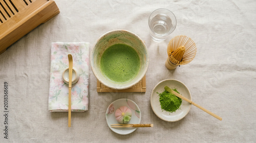 Fotografía Overhead view of a traditional Japanese matcha tea ceremony set, featuring a foamy green tea bowl, bamboo tools, vibrant powder, and a delicate wagashi sweet