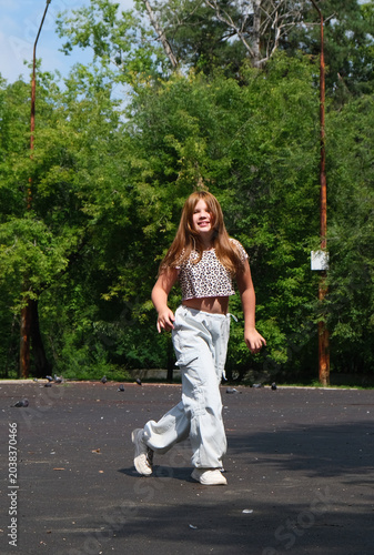 Happy young girl enjoys walking, dancing and jumping freely in the summer sun. Blurred motion captures the energy of the moment, celebrating freedom, carefreeness and individuality. 