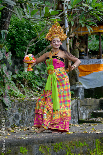 Billede på lærred Balinese female dancer in elaborate golden crown and colorful sarong posing besi