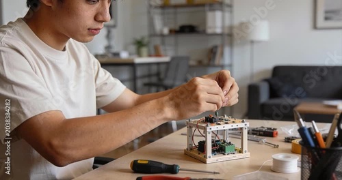 Young person assembling electronic component prototype indoors