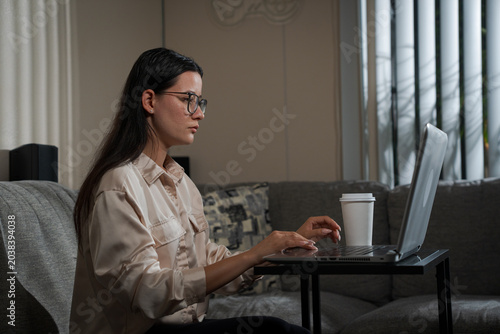 Woman working on laptop at home with coffee daytime showing modern remote work lifestyle and comfortable home atmosphere
