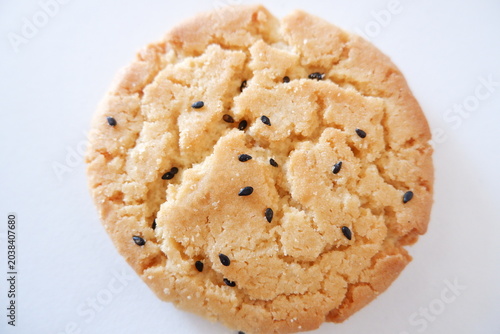 Canvastavla Close-up of crunchy sesame biscuit on white background, golden baked cookie with black sesame topping and crumbly texture