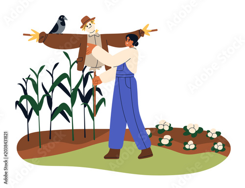 Farmer installing scarecrow in vegetable garden for harvest and crop protecti...