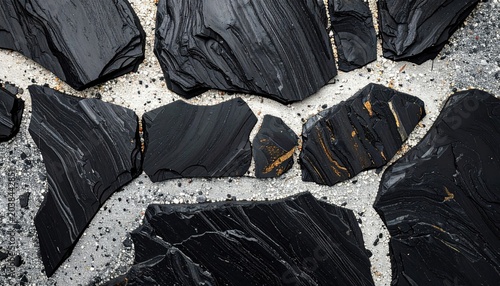 Raw Obsidian Chunks Scattered on a Textured Gray Surface.