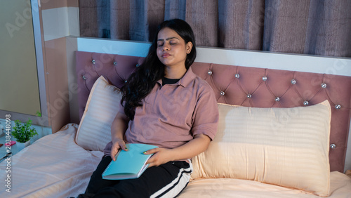 Fotografía Indian Woman Falling Asleep While Reading Book on Bed at Home