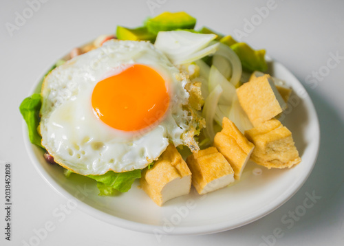 Fried egg with salad and crackers on white plate, stock photo