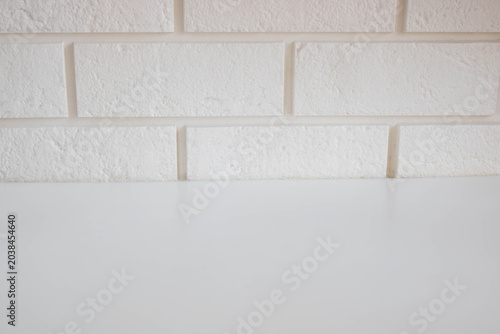 A glossy, empty table surface against a white brick wall