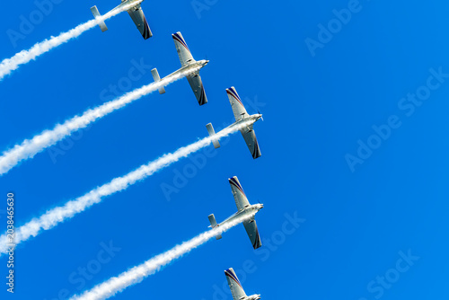 Airshow performance with aircraft, flight of pilotage team with colorful smoke trails. Planes and jets in the air. Flight show of air force team with group of planes in blue sky.