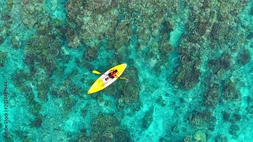 Aerial  view of a woman relaxing on a yellow kayak over a beautiful coral reef in crystal clear turquoise sea water background 	