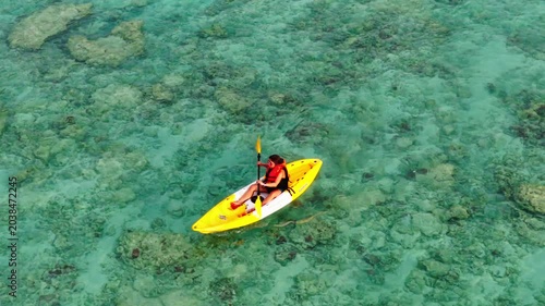 Aerial  view of a woman relaxing on a yellow kayak over a beautiful coral reef in crystal clear turquoise sea water background 	