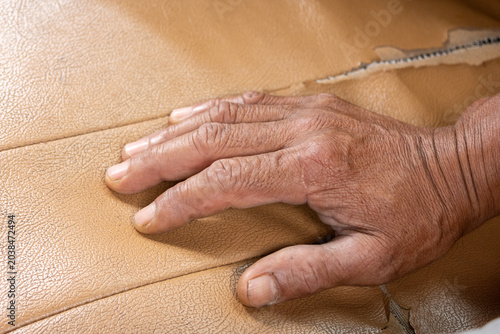 Tableau sur toile Wrinkled hand resting on cracked torn leather surface feeling nostalgic connecti