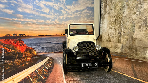 Bild auf Leinwand An antique 1920s vintage roadster convertible car displayed with a coastal sunset road backdrop at the Old Transportation Museum in Rasamadu Heritage, Central Java