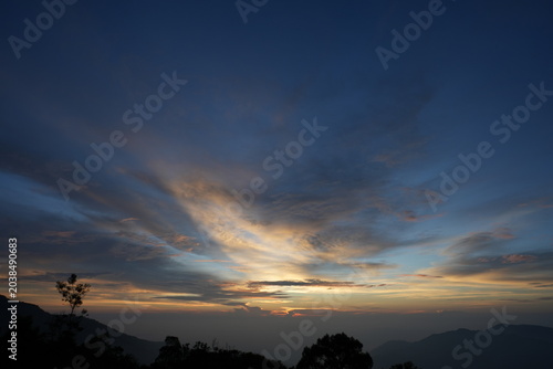 sunrise with mountain, trees, hills, shadows and morning fog