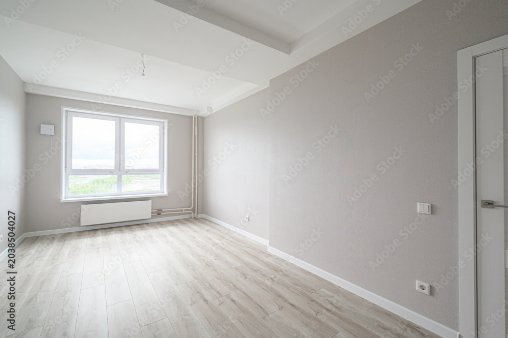 Fototapeta premium bright empty room with light grey textured walls, light wood laminate flooring, a large double window with a white radiator below, and white ceiling