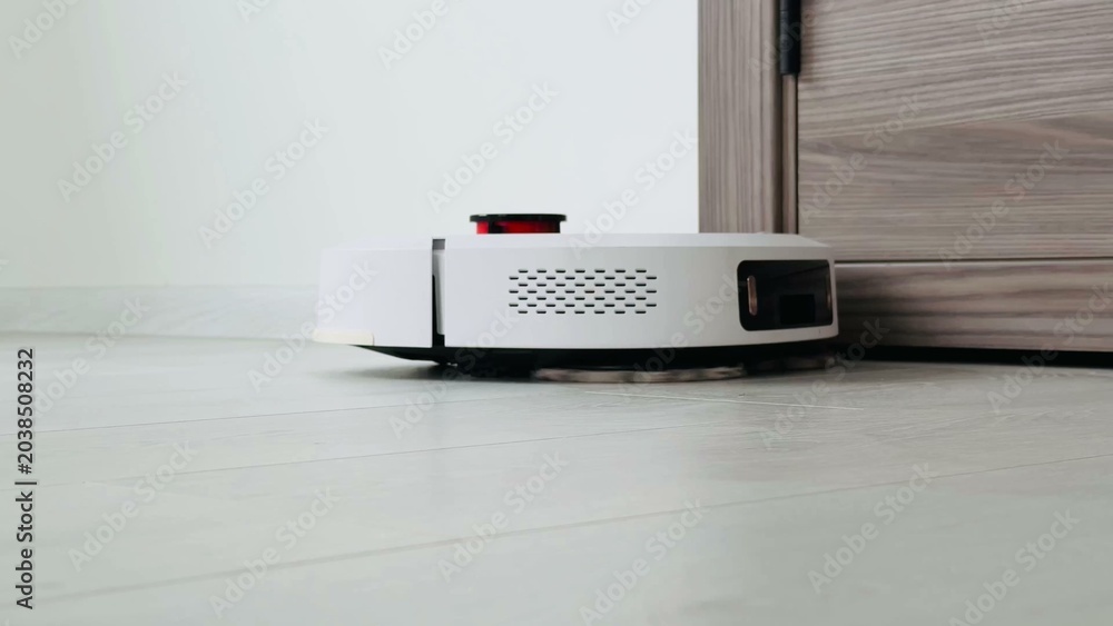 Fototapeta premium Robotic vacuum cleaner navigating smooth floor near door threshold with contemporary design