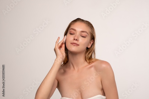 Konstfotografi Young woman cleaning her face with a cotton pad, enjoying a refreshing skincare