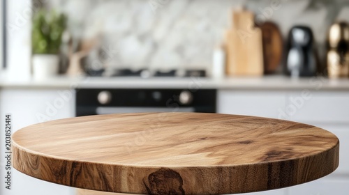 Empty round wooden table in a modern kitchen. Blurred background of white cabinets, countertops, and appliances