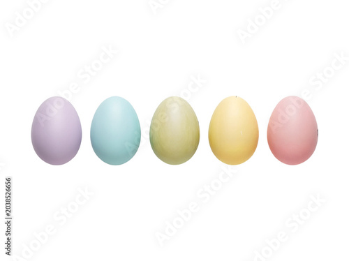 Five pastel colored Easter eggs arranged in a row on polka dot background