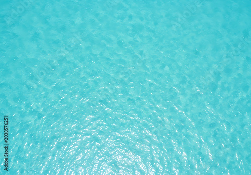 Aerial view of turquoise ocean water with subtle wave patterns and sun reflections tropical seascape