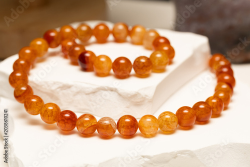Cracked agate beads are arranged on a white stone surface. These stones are used to make bracelets and necklaces for people who enjoy wearing unique jewelry.