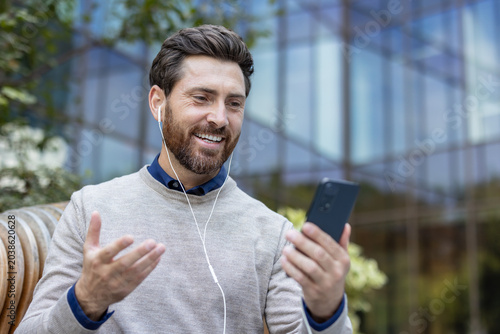Foto Happy man having video call using smartphone outdoors