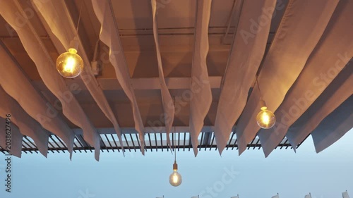 Pendant Globe Bulbs Hanging Under Pergola With Draped Fabric Canopy at Dusk Outdoor Ambiance