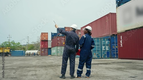 Diverse Two Logistics Workers in Hard Hats Inspecting Shipping Stacked Containers in Container Yard