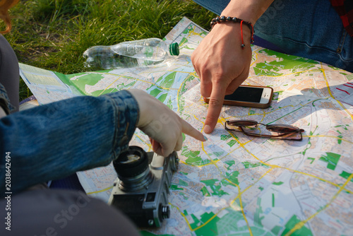 Young couple planning a hiking route with a paper map and vintage camera.